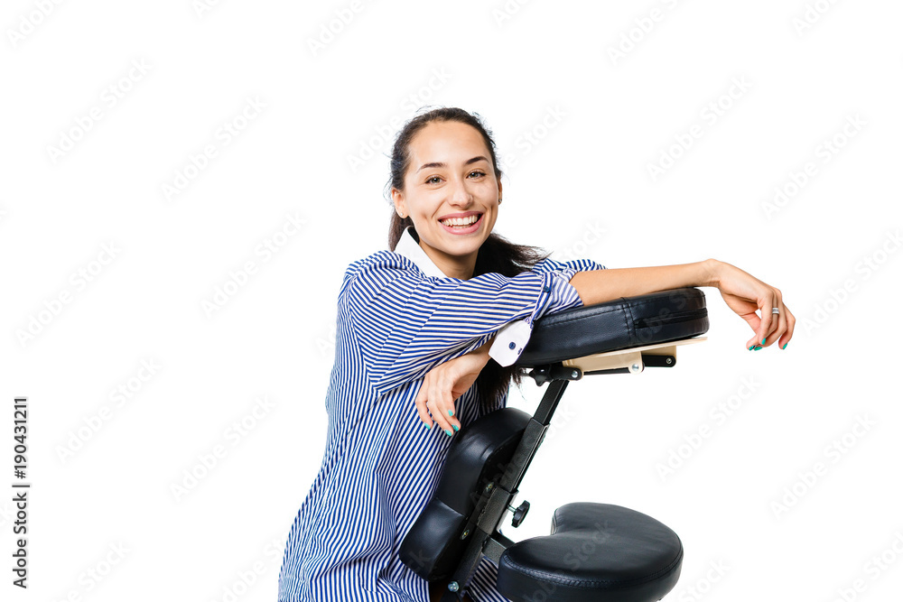 Young beautiful girl brunette office worker in a shirt and with bare legs sitting on a massage chair. Dark skin and hair of a brunette. Business concept and massage Young beautiful girl brunette office worker in a shirt and with bare legs sitting on a massage chair. Dark skin and hair of a brunette. Business concept and massage