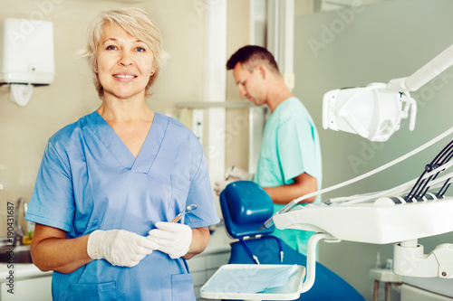 Dentist near dental chair  welcoming patient to office
