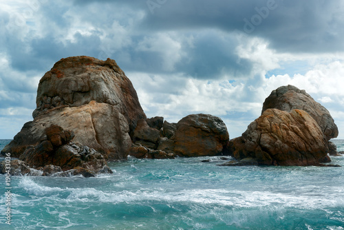 Sea landscape with rock in ocean, dark clouds in sky