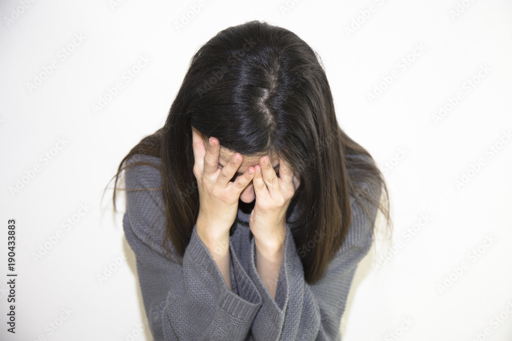 Closeup portrait of a stressed woman in a deep pain. Her face is pressed against her hands. Alone and lonely young girl feeling depressed. Closeup portrait of a stressed woman in a deep pain. Her face is pressed against her hands. Alone and lonely young girl feeling depressed.