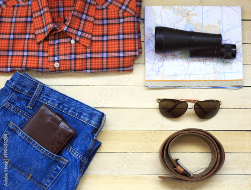 Men's casual outfits with man clothing, travel preparations and accessories on wooden background
