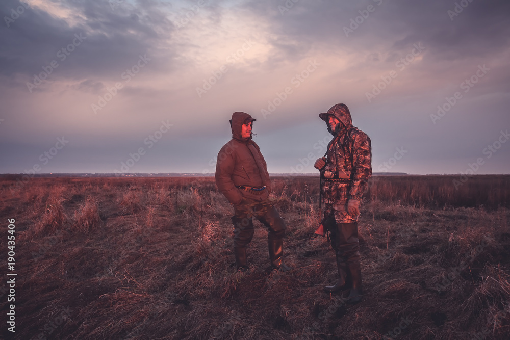 Hunters during hunting spring season in rural field at sunrise - obrazy, fototapety, plakaty 