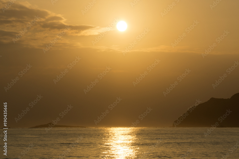 Naklejka premium Sunrises in between Kaohikaipu (Black/Turtle) Island and Makapuu with sunlight reflecting on the ocean water of Waimanalo bay