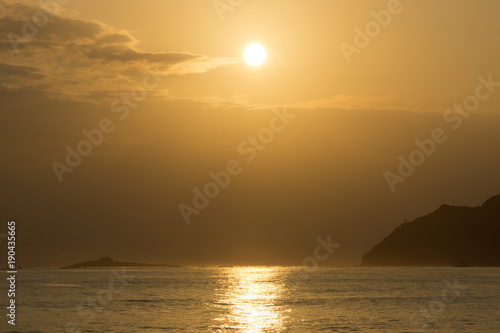 Sunrises in between Kaohikaipu (Black/Turtle) Island and Makapuu with sunlight reflecting on the ocean water of Waimanalo bay