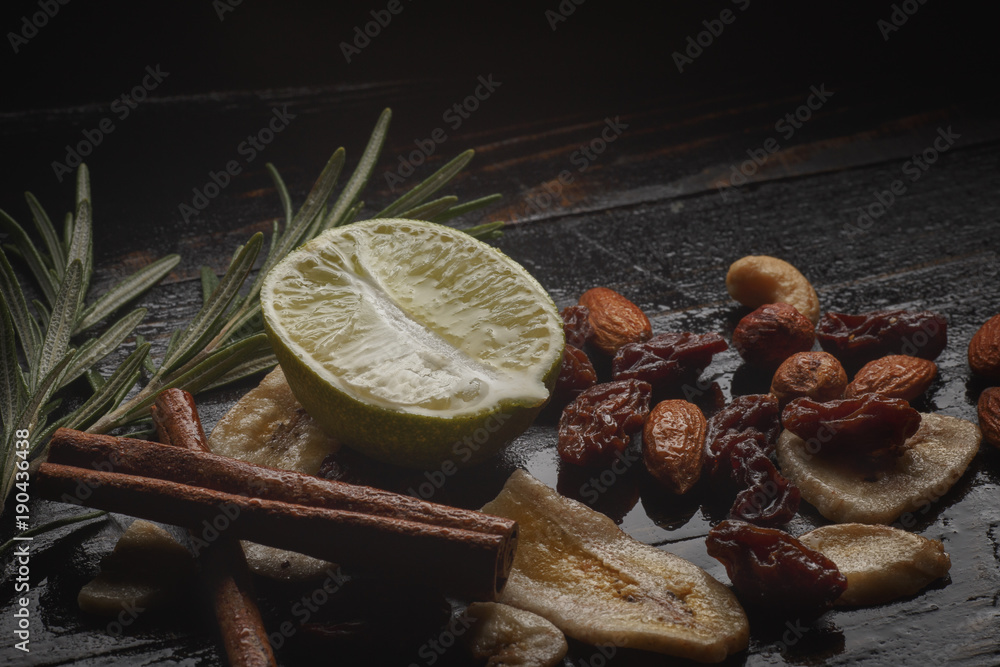 Mix of nuts, dried fruits and herbs on a black rustic background.