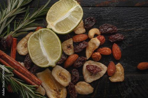 Mix of nuts, dried fruits and herbs on a black rustic background.