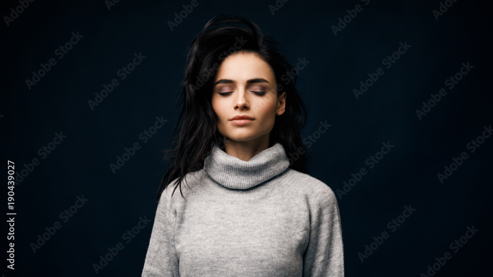 Beautiful brunette woman standing in studio with her eyes closed Beautiful brunette woman standing in studio with her eyes closed
