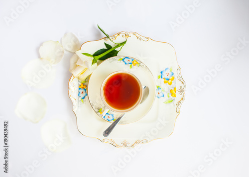 flatlay with elegant tea set with rose flower reflection iat the urface of liquid surrounde by rose petals and flowers photo