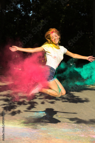 Funny young woman jumping with vibrant colors exploding around her