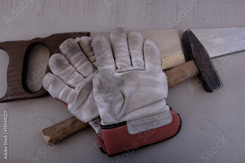 Werkzeug-Stillleben mit Arbeitshandschuh, Säge und Hammer photo