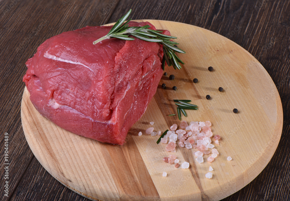 Raw fresh meat with rosemary on a round cutting board