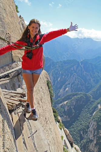 A girl walks along a Danger trail on the sacred mountain of Huashan, near Xian. China.
