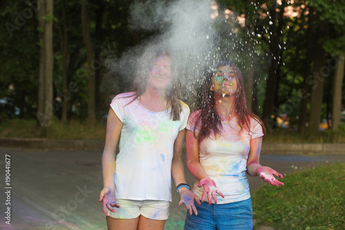 Two smiling friends having fun with Holi paint in the park