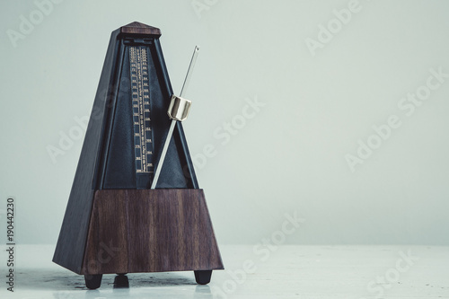 Color shot of a vintage metronome, on gray background. photo