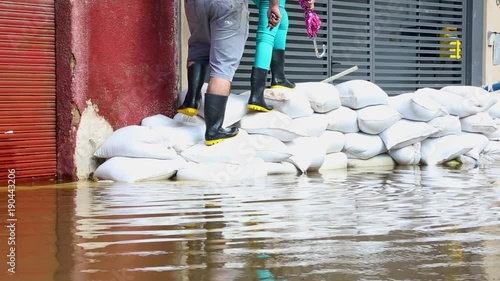 Man and woman climb onto sandbag barrier to avoid flood water photo