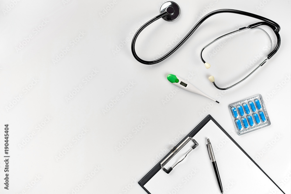 Stethoscope in the office of doctors.Top view of doctor's desk table, blank paper on clipboard with pen. Copy space. Designer's blank Stethoscope in the office of doctors.Top view of doctor's desk table, blank paper on clipboard with pen. Copy space. Designer's blank