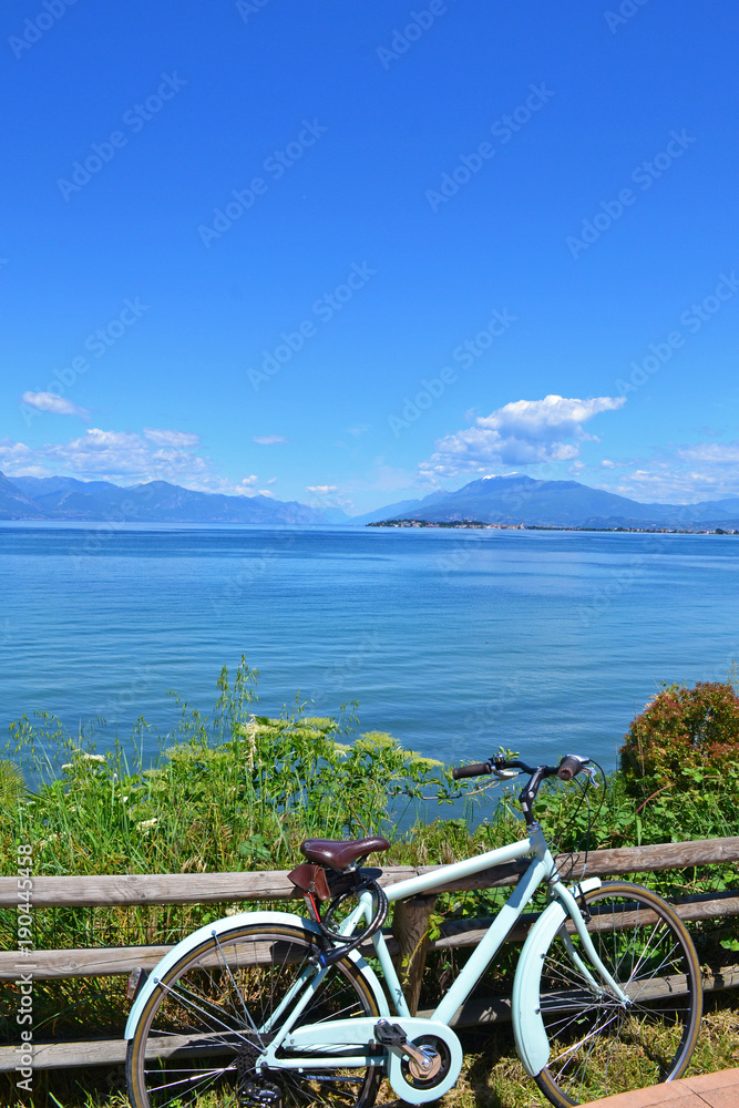 Bike next to Lake Garda landscape, with mountains in the background, Italy