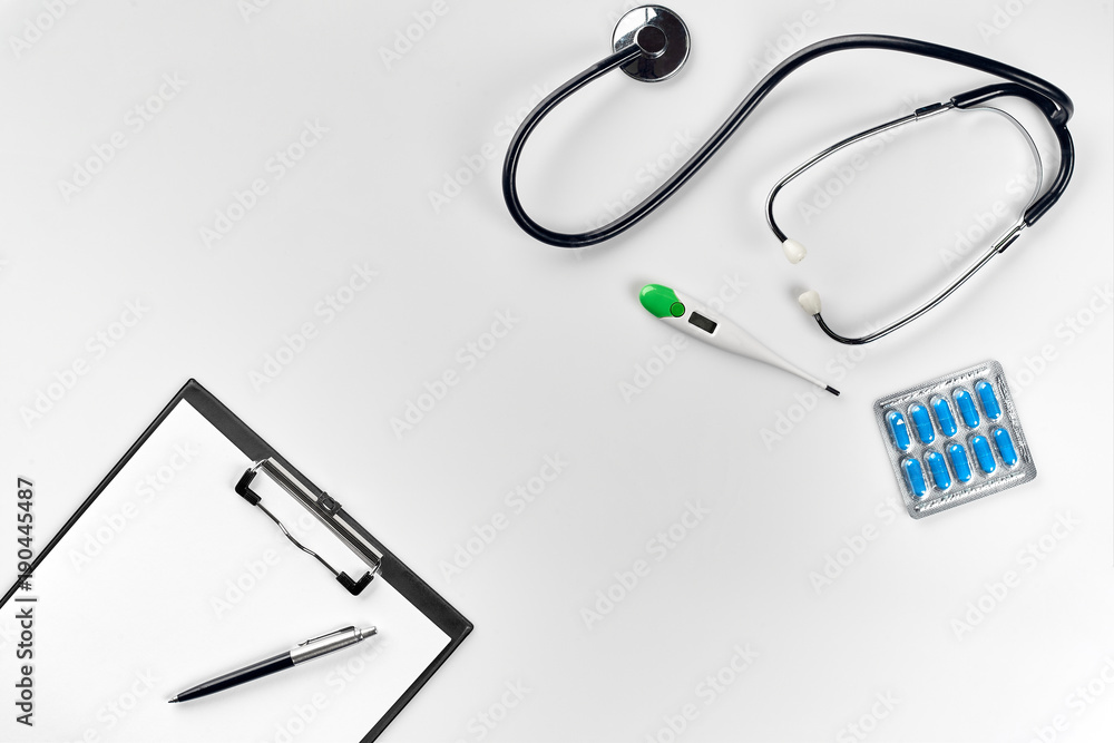 Stethoscope in the office of doctors.Top view of doctor's desk table, blank paper on clipboard with pen. Copy space. Designer's blank Stethoscope in the office of doctors.Top view of doctor's desk table, blank paper on clipboard with pen. Copy space. Designer's blank