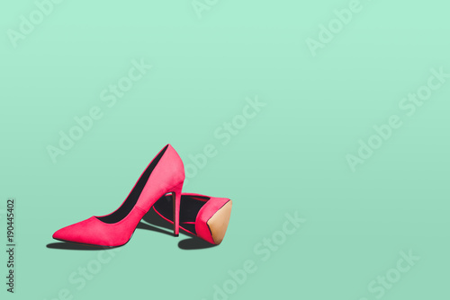 Fototapeta Red high heels isolated on a bright green pastel background