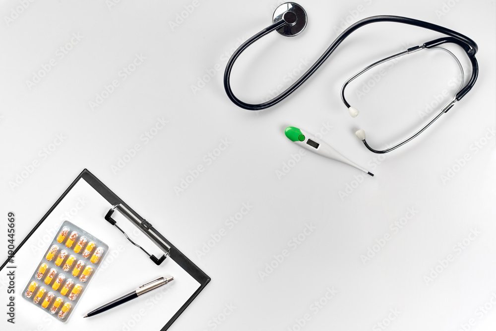 Stethoscope in the office of doctors.Top view of doctor's desk table, blank paper on clipboard with pen. Copy space. Designer's blank Stethoscope in the office of doctors.Top view of doctor's desk table, blank paper on clipboard with pen. Copy space. Designer's blank