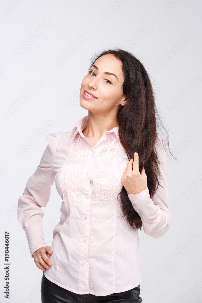 Portrait of a young woman with a charming toothy smile, black hair and brown eyes on a white background in a pink shirt. Positive and joyful emotions Portrait of a young woman with a charming toothy smile, black hair and brown eyes on a white background in a pink shirt. Positive and joyful emotions