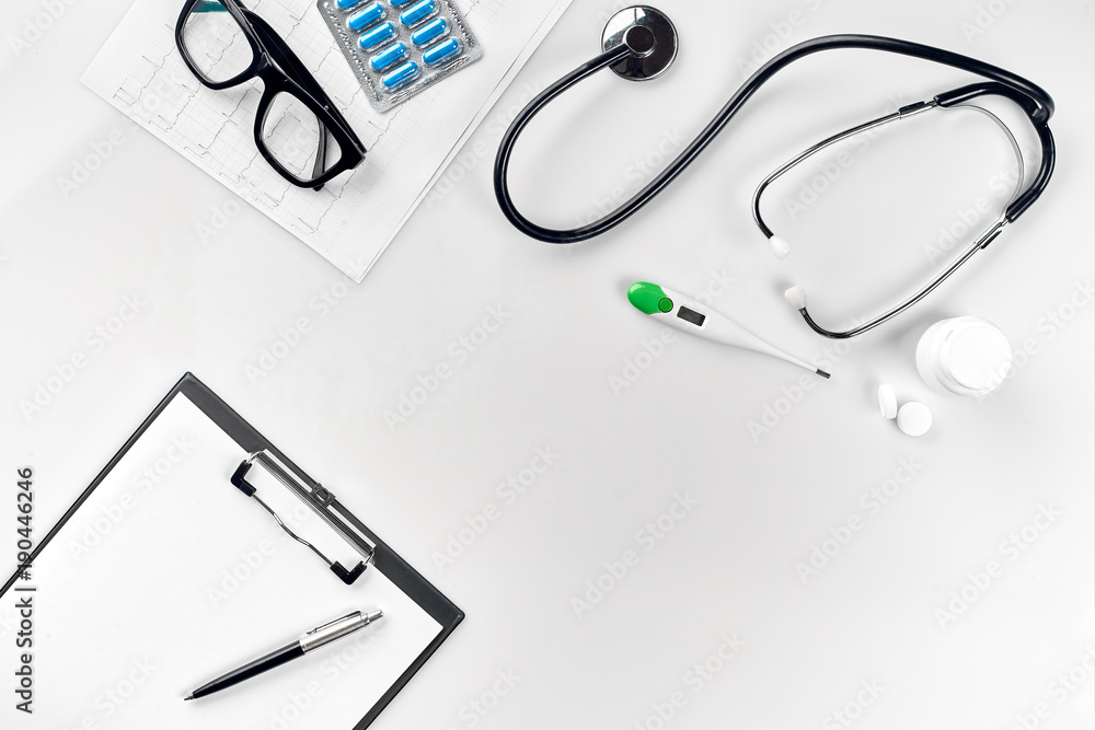 Stethoscope in the office of doctors.Top view of doctor's desk table, blank paper on clipboard with pen. Copy space. Designer's blank Stethoscope in the office of doctors.Top view of doctor's desk table, blank paper on clipboard with pen. Copy space. Designer's blank