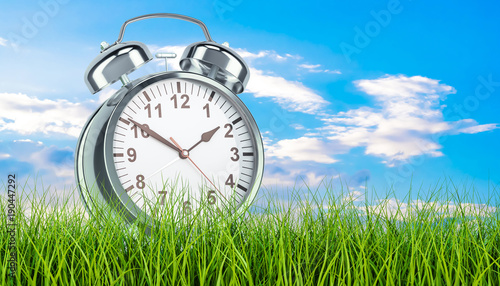 Fotografie Alarm clock in green grass, 3d rendering