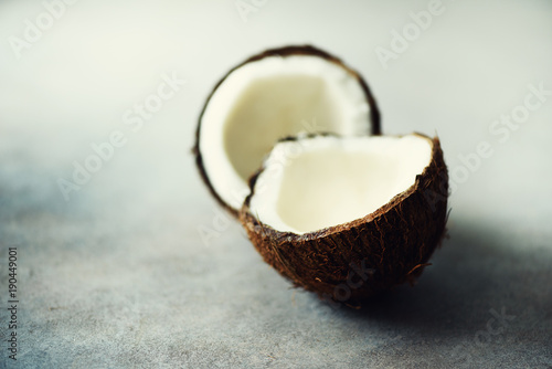 Cracked two halves of fresh organic coconut on grey background. Copy space