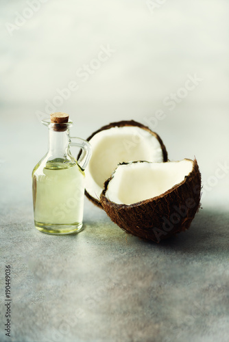 Cracked two halves of fresh organic coconut and coconut oil on grey background. Copy space