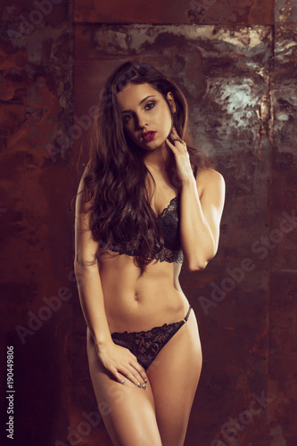 Amazing young woman with perfect body wearing black lingerie  posing in the dark