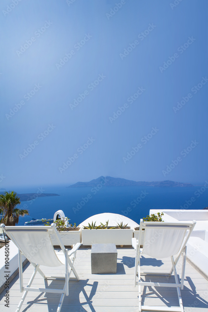 Sunbeds on the terrace of hotel. Santorini island, Greece. Beautiful summer landscape with sea view