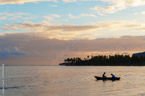 two fishermen in a boat going fishing early in the morning at dawn