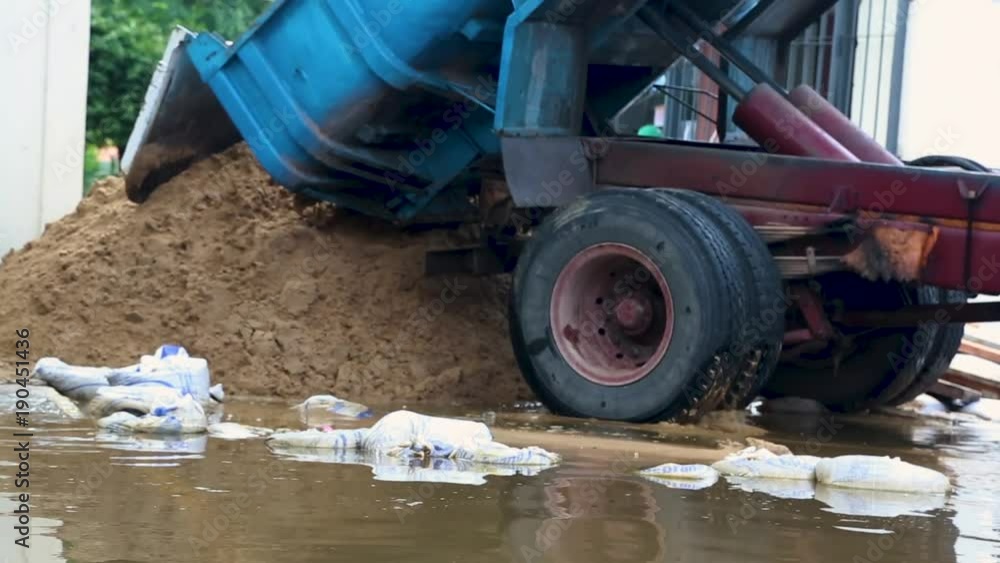 Dump truck finished dumping a load of sand on a flooded street Dump truck finished dumping a load of sand on a flooded street