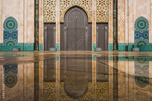 view of Hassan II mosque's big gate reflected on rain water - Casablanca - Morocco photo