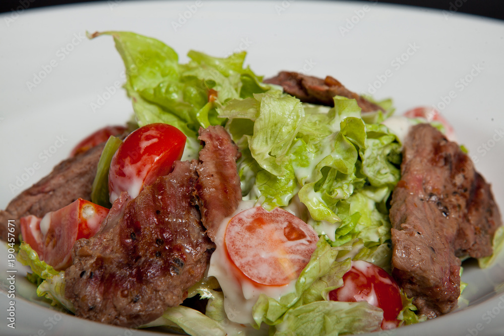 Veal salad, salad with large slices of veal and fresh vegetables on a plate Veal salad, salad with large slices of veal and fresh vegetables on a plate