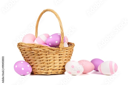 Easter basket filled with colorful hand painted pink, purple and white Easter Eggs over a white background