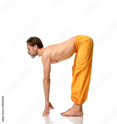 Old man practicing yoga doing sport stretching exercises in yellow pants 