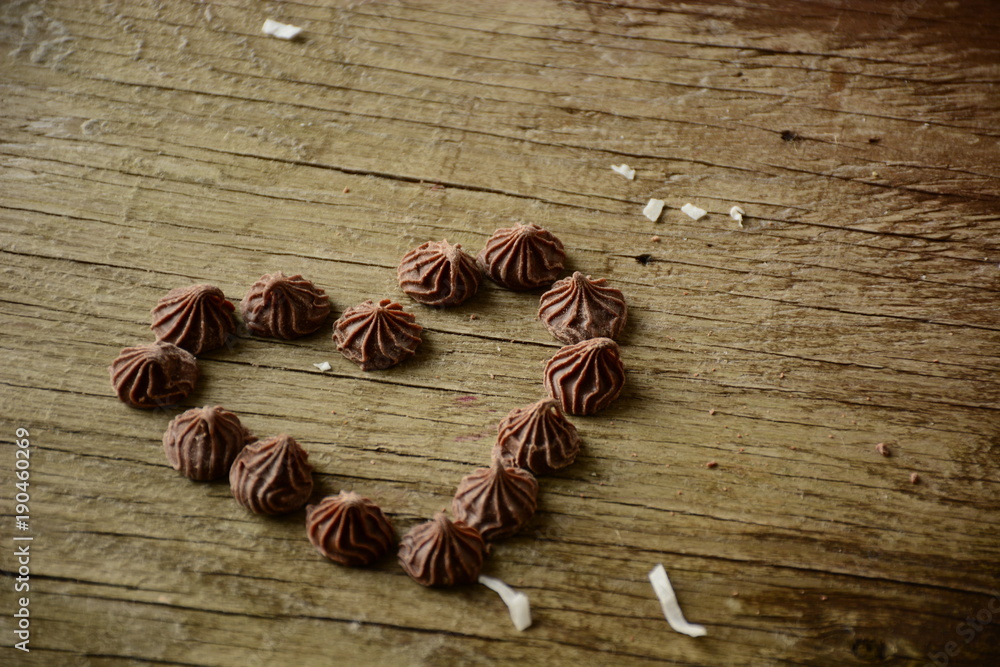 Piece of cake napoleon on a plate with custard and coconut chips. Heart maked with chocolate candys on wooden background Piece of cake napoleon on a plate with custard and coconut chips. Heart maked with chocolate candys on wooden background