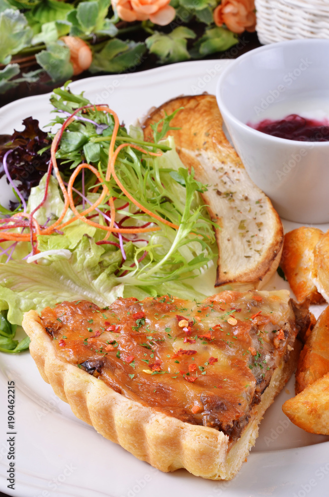 A slice of bacon and cheese quiche lorraine on a white plate A slice of bacon and cheese quiche lorraine on a white plate