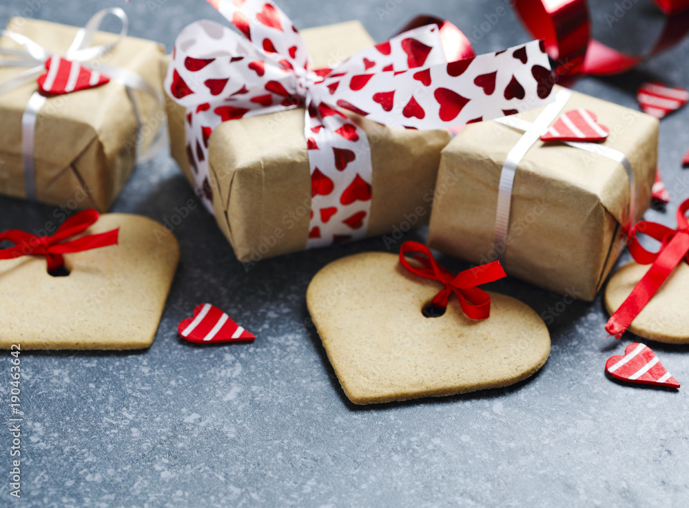 Gift boxes with decorative red hearts and heart shaped cookies. Festive background. Flatlay with copy space. Gift boxes with decorative red hearts and heart shaped cookies. Festive background. Flatlay with copy space.