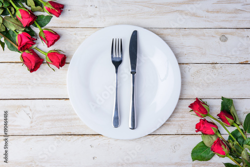 Romantic table Red roses knife, spoon, plate and hearts on old white wood table/Valentines day background