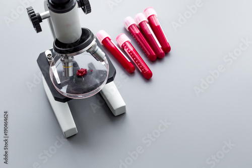 Do blood test in laboratory. Analysis. Blood samples in test tubes near microscope on grey background top view copy space