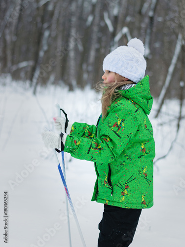 Girl running on skis in the woods in profile.