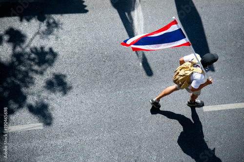 A man walking on street with Thai Flag on shoulder, political activist