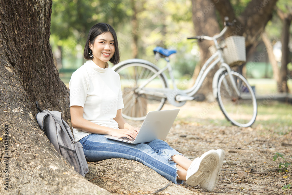 Asian Woman using laptop with attractive smiling at garden. People lifestyle concept.