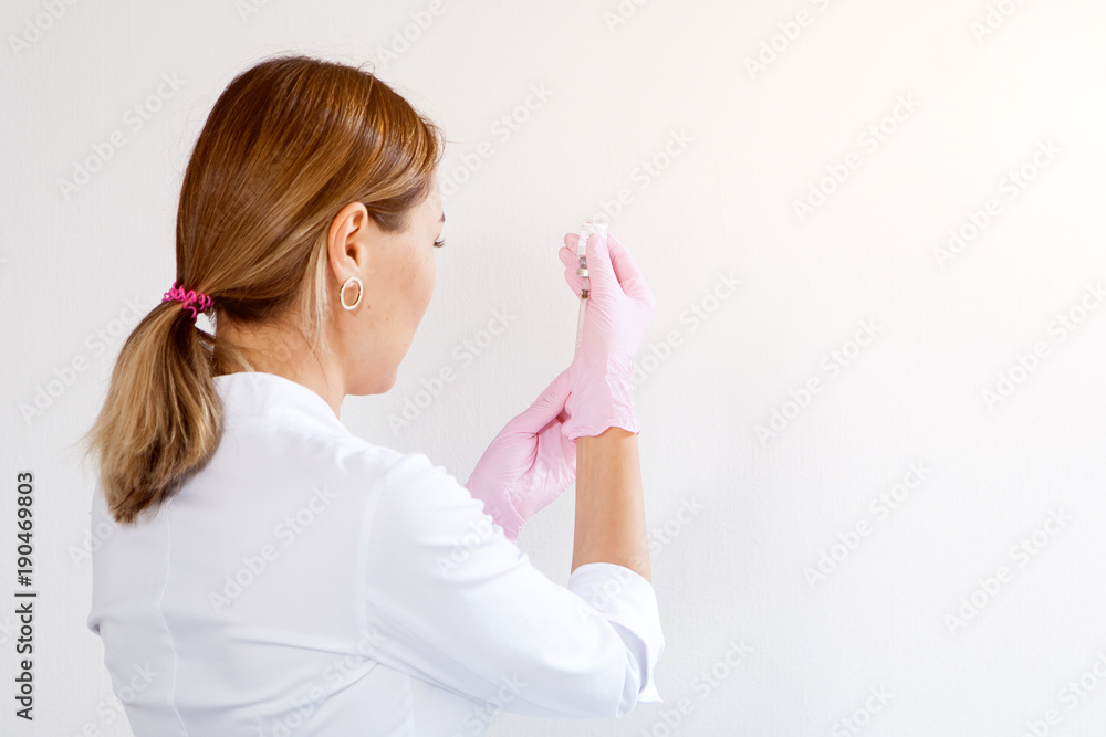 Dark-haired woman asian beautician in sterile gloves prepares syringe for cosmetic procedure in the medical office Dark-haired woman asian beautician in sterile gloves prepares syringe for cosmetic procedure in the medical office
