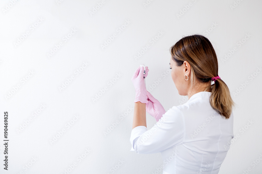 Dark-haired woman asian beautician in sterile gloves prepares syringe for cosmetic procedure in the medical office Dark-haired woman asian beautician in sterile gloves prepares syringe for cosmetic procedure in the medical office