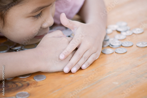 Cute asian little child girl hugging and stingy her money. Kid saving money for the future concept
