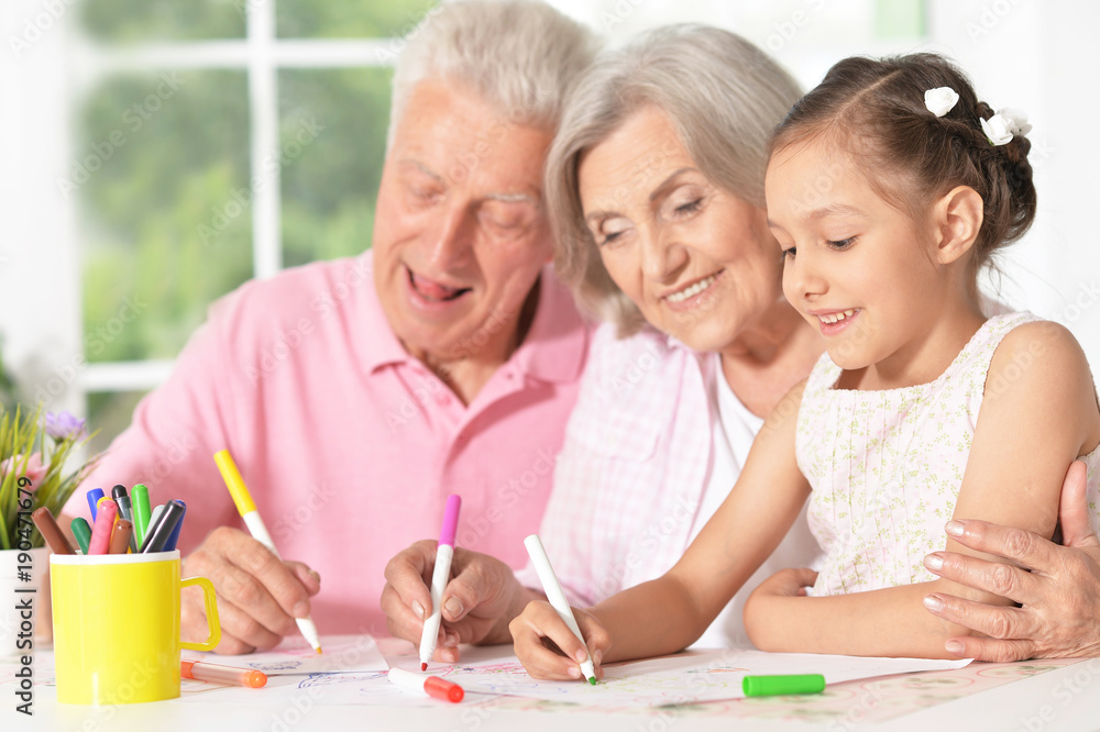 girl with grandparents drawing at the table girl with grandparents drawing at the table