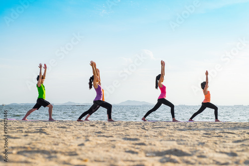 Yoga class at sea beach in sunset time  Group of people doing Warrior poses with clam relax emotion at beach Meditation pose Wellness and Healthy balance lifestyle.